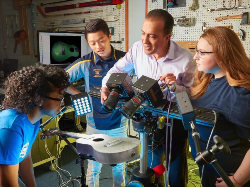 Students collaborate with a professor in Kettering University's Noise, Vibration, and Harshness and Experimental Mechanics Laboratory, using advanced imaging technology to study acoustic properties of a guitar.